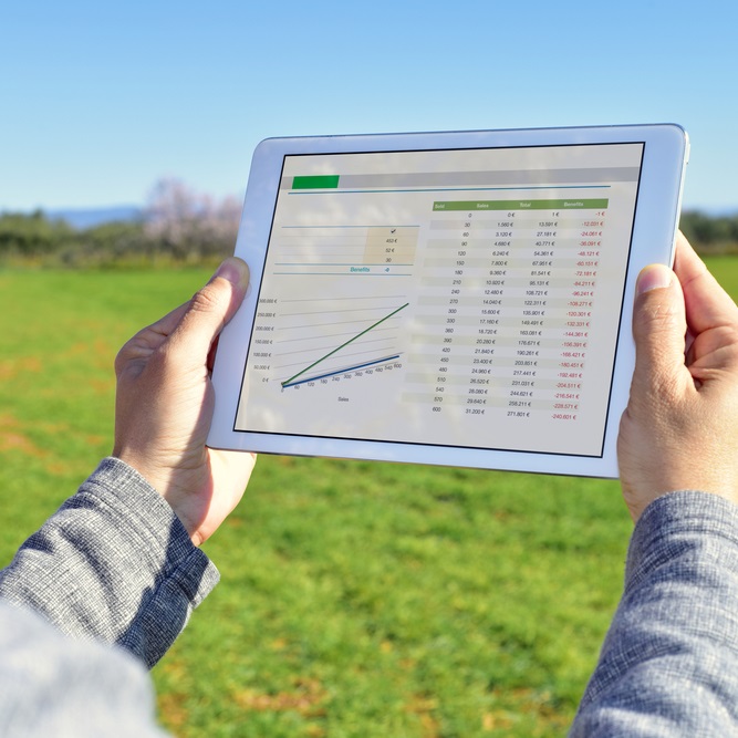 Graphs on iPad held in 2 hands with background of a paddock